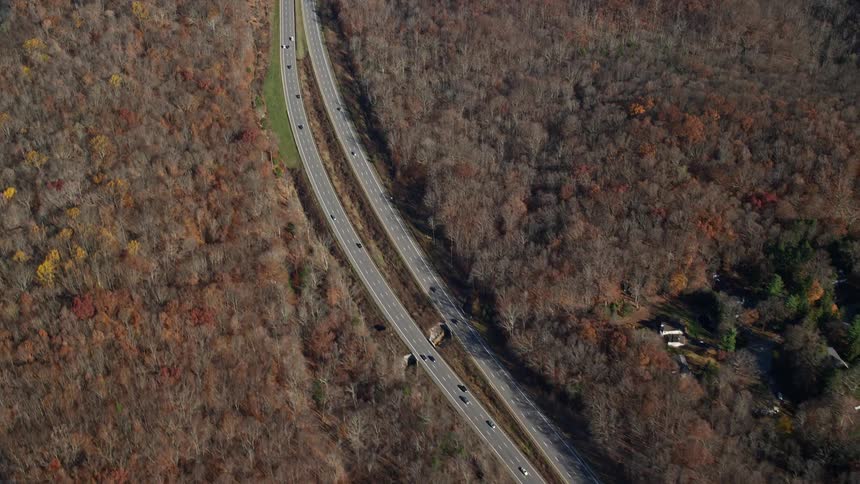 Aerial view of highway through fall trees and rural neighborhood