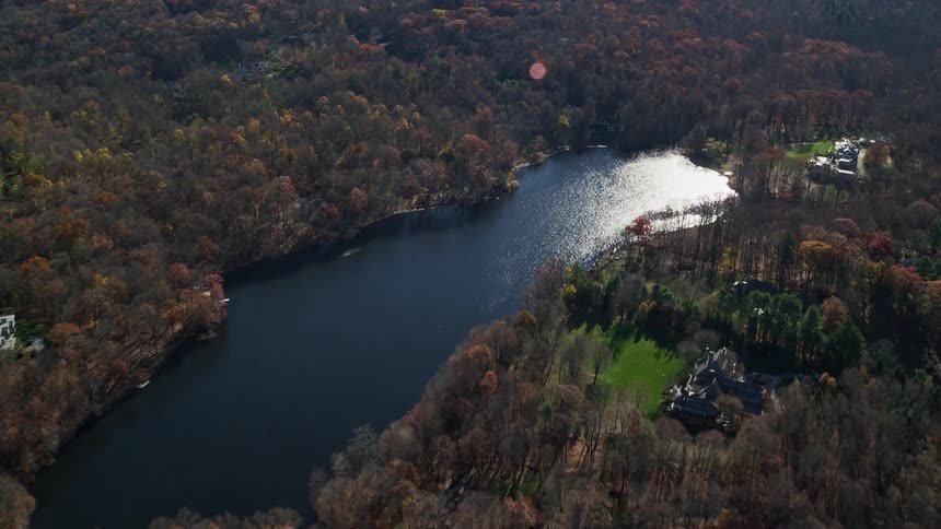 Aerial panorama of a forest with a central lake and sunlight reflection