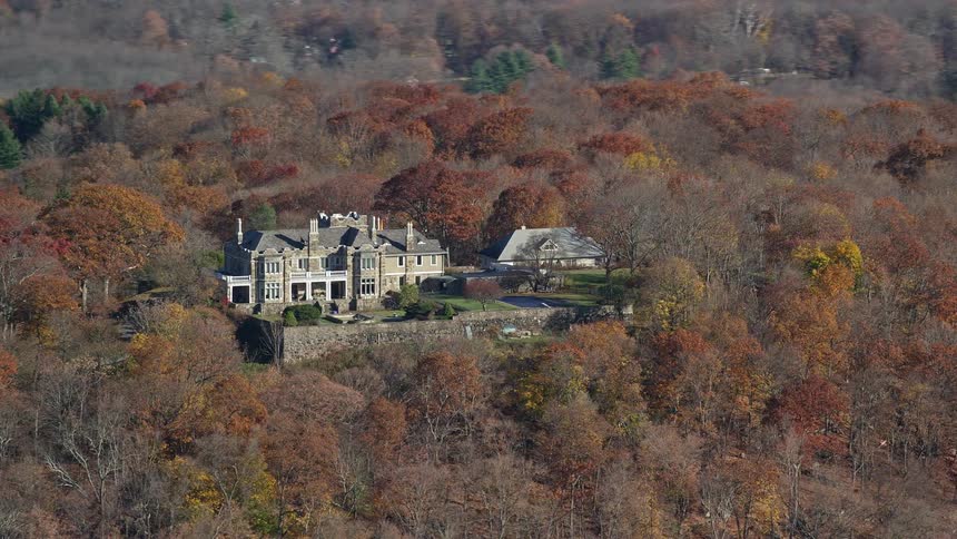 Aerial view of a mansion on a hill with extensive tree vegetation
