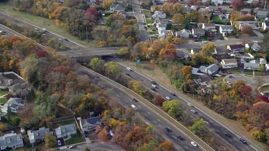 Aerial view of cars on freeway driving by suburbs in fall