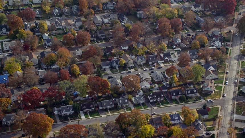 Aerial of houses and moving cars in a suburban area on a sunny day