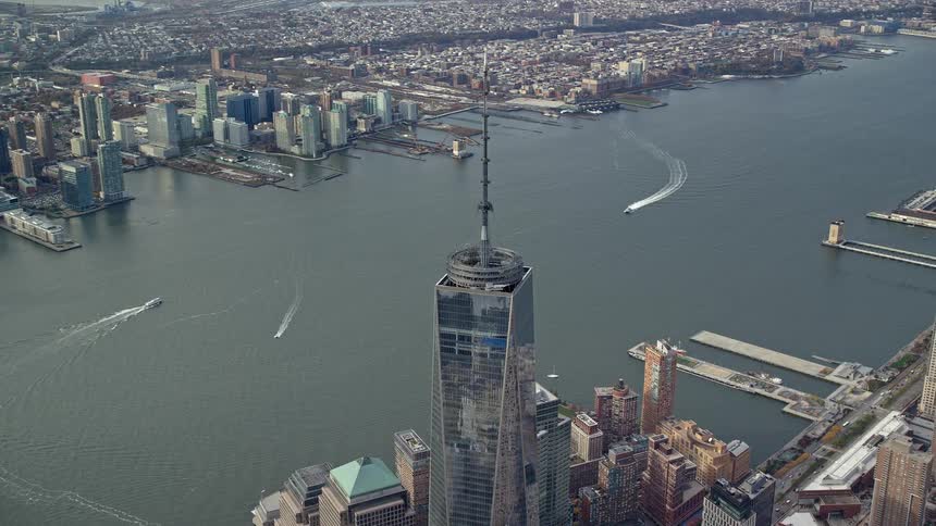 A city skyline showing a river with some boats moving along the river is lined by skyscrapers on both sides and there are also piersdocks