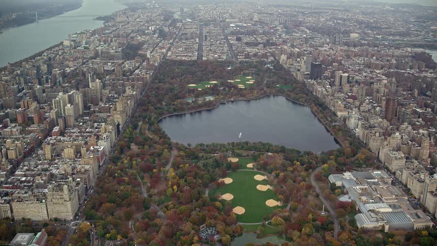Aerial panorama of a central park with a lake in the midst of a metropolis