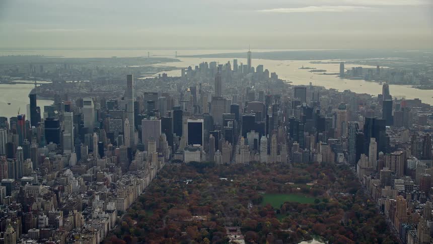 Aerial view of a square full of trees surrounded by a city with lots of buildings and a lake