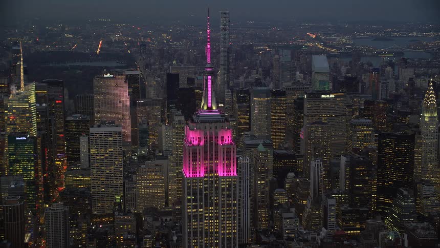 A building in a metropolitan city with pink lights on top