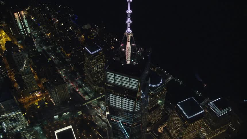 Aerial view of a metropolis at night with a mirrored tower in skyscrapers by the seaside