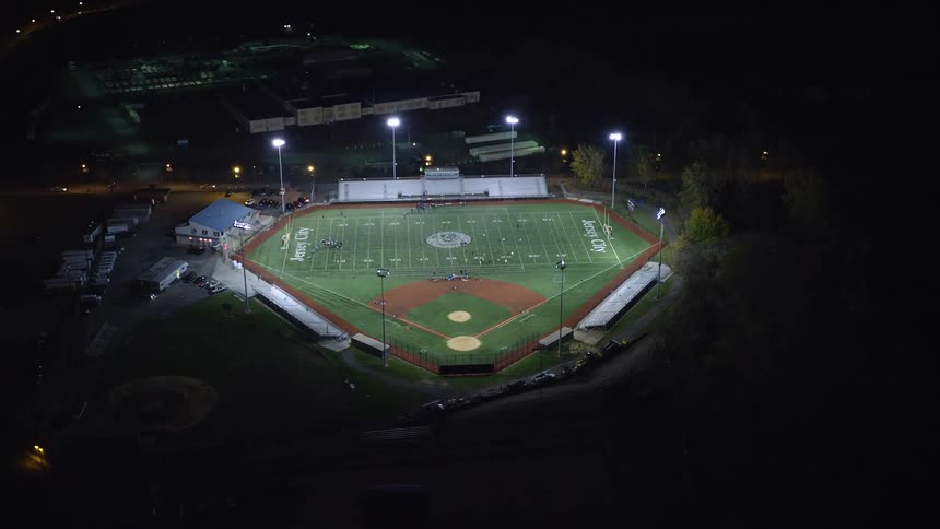 Aerial view of a stadium illuminated at night in the midst of a city