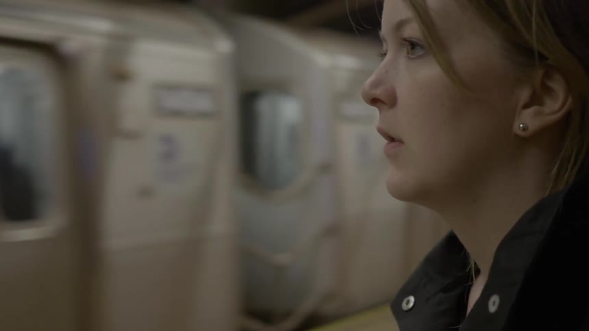A woman waits for the subway to stop
