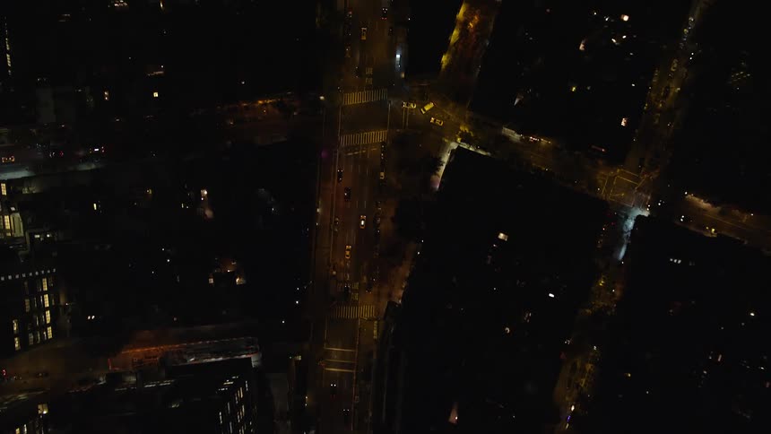 An aerial view of a night city streets with cars passing by