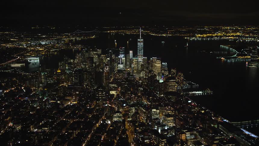 Aerial of downtown skyscrapers bordering river at night