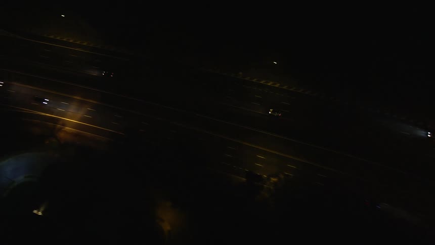 An aerial view of a highway with several cars passing by at night