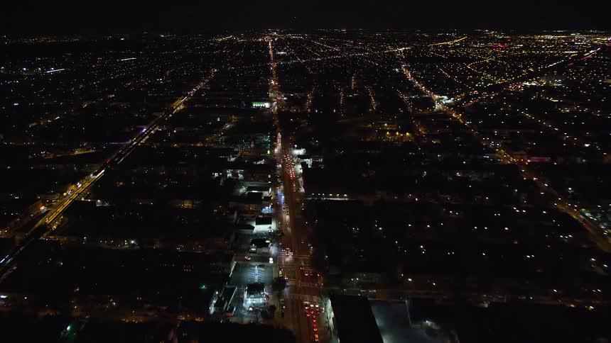 Aerial of traffic flowing along brightly lit city streets at night