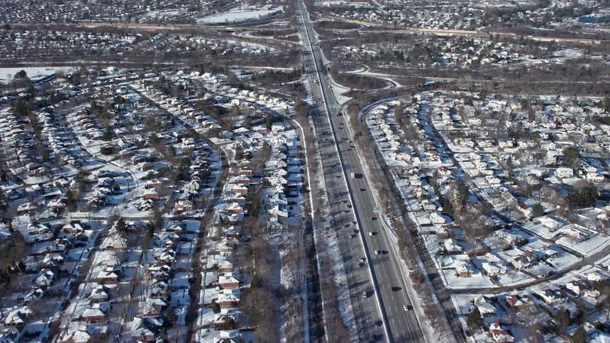 An high way goes through a sub urban area with the whole place covered in snow