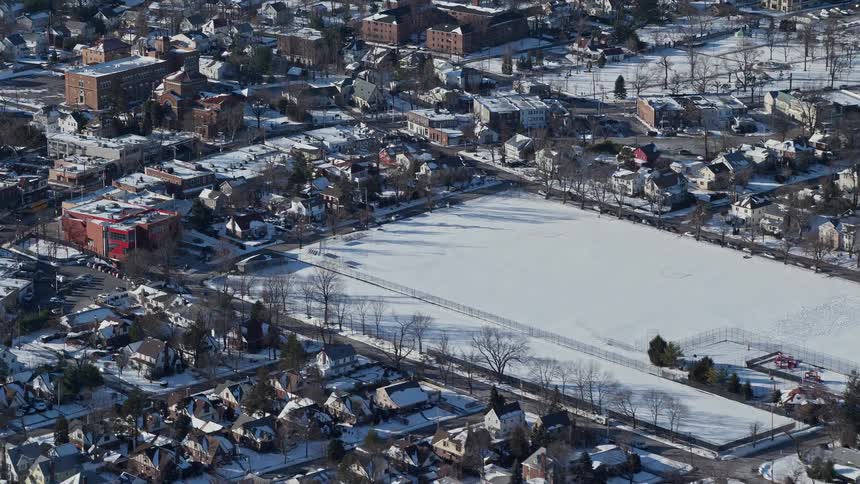 Aerial view of a central park covered in snow and surrounded by a residential neighborhood
