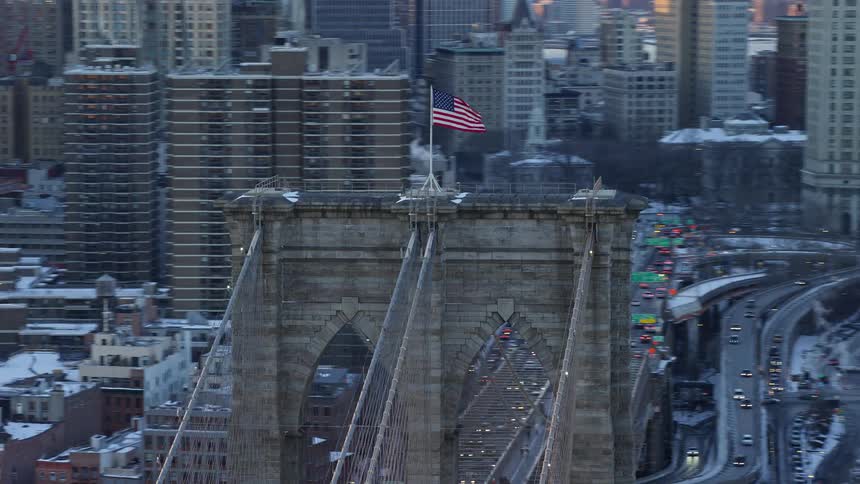 United states flag on top of a bridge in the midst of a metropolitan city
