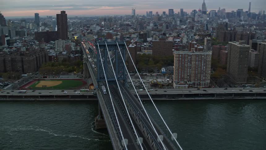 A bridge liking a large city with a busy highway beside the shore