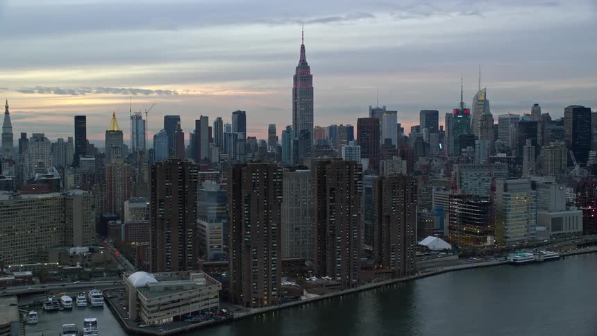 Aerial of downtown skyscrapers bordering waterfront under a red tinted sky