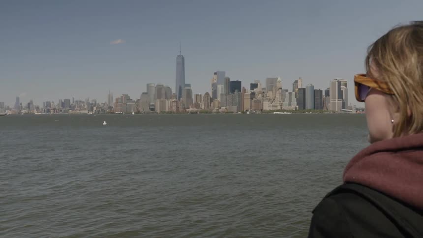 A woman overlooks the water before a large city