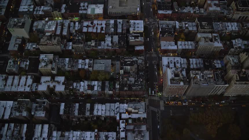 Aerial of buildings and cars moving in a city at dusk
