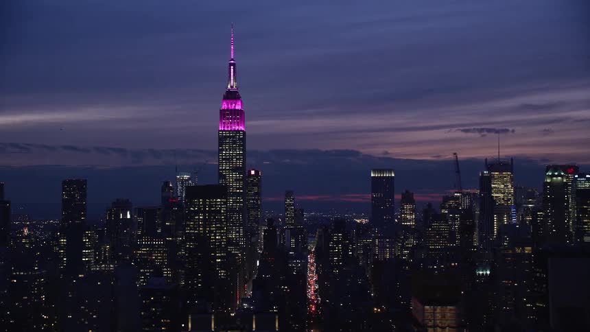 Aerial panorama of a metropolis with skyscrapers illuminated under a purple dusk sky