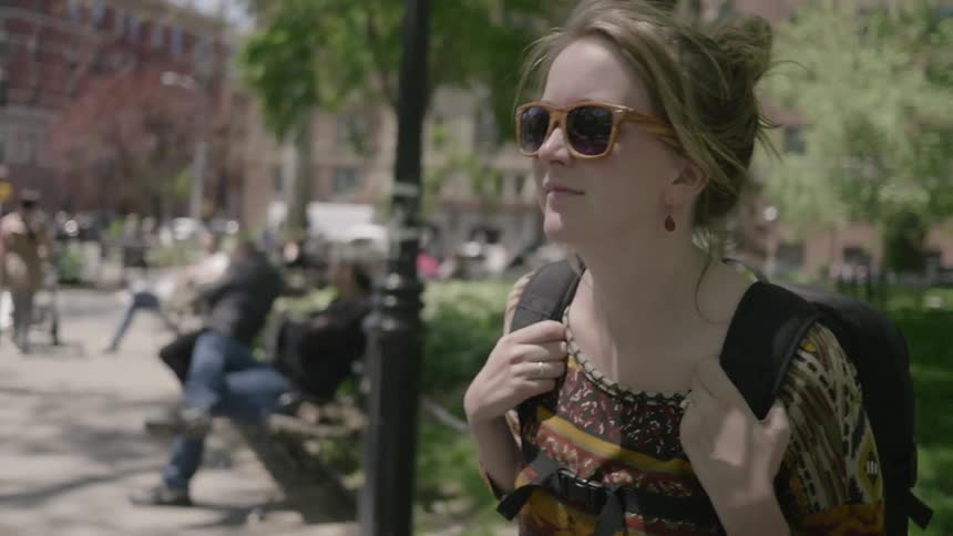 A woman turns and begins walking on the sidewalk