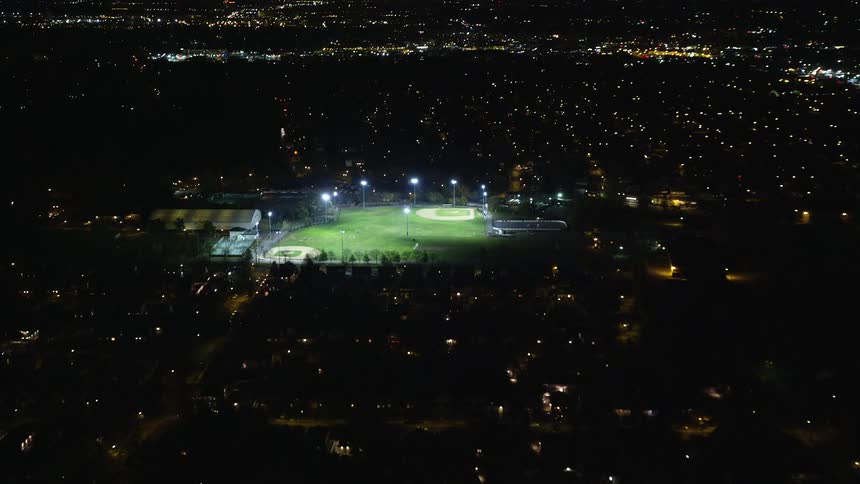 Aerial view of urban area at night with green athletic field