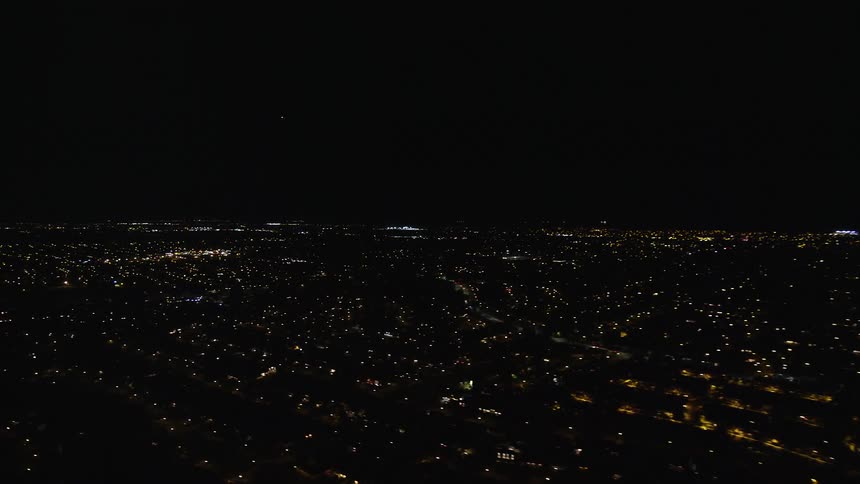 An aerial view of a city at night with house and car lights on