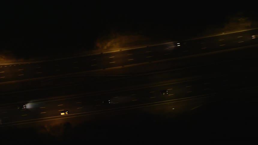 Aerial of cars moving quickly along a separated highway at night