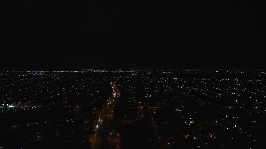 Aerial of a neighborhood with a main highway with dense traffic at night