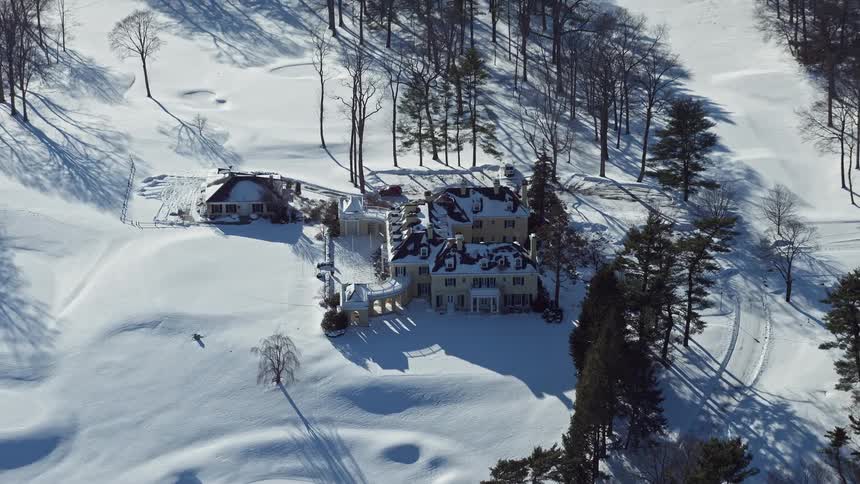 A house in a rural area all covered in snow and surrounded by trees
