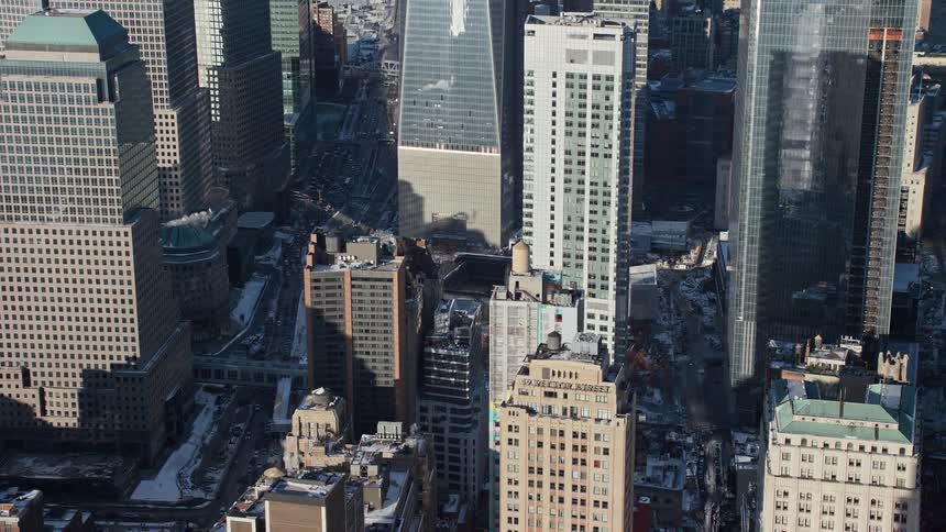 A sunny day in the city during winter as snow is covering some the roads and low structures