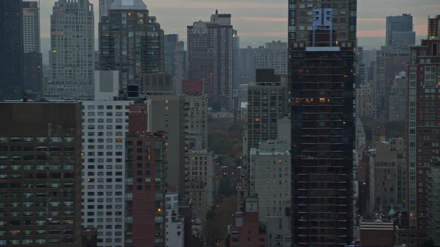 Traffic flows along downtown streets between skyscrapers under a cloudy dawn sky