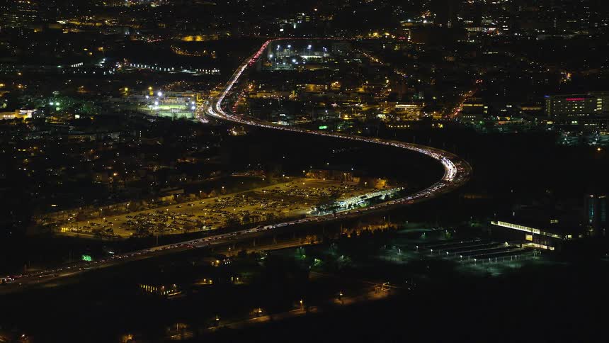 Aerial of moving cars on a highway in a metropolitan area at night