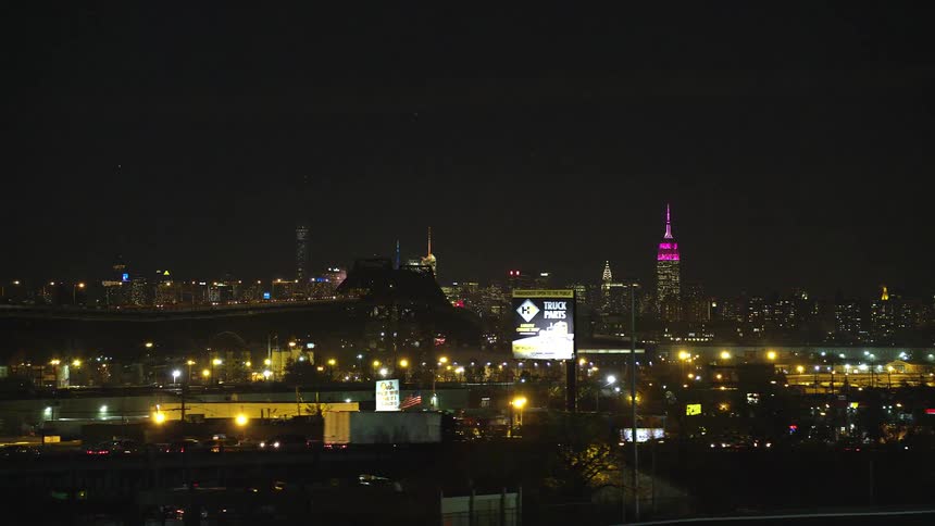 The city is brighten with electricity at night with cars going by a busy road