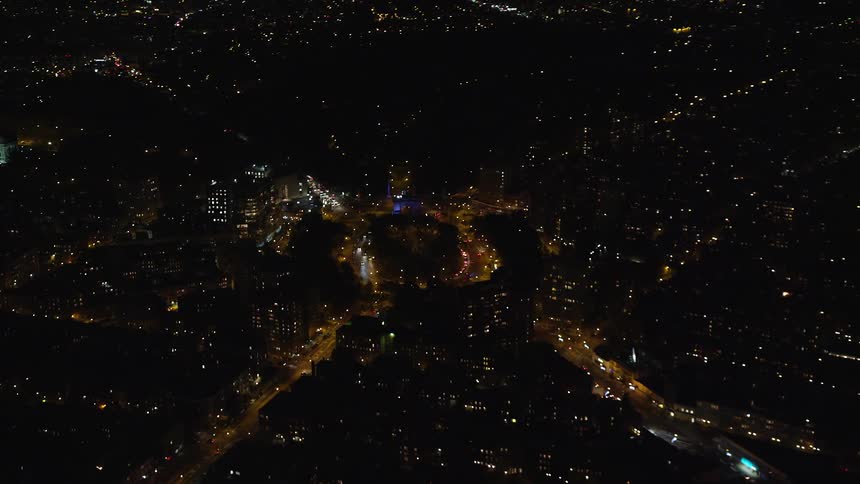Aerial of buildings and moving cars on roads in a city at night