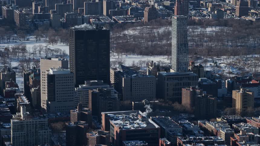 Aerial view of a metropolis with buildings in a central park covered in snow