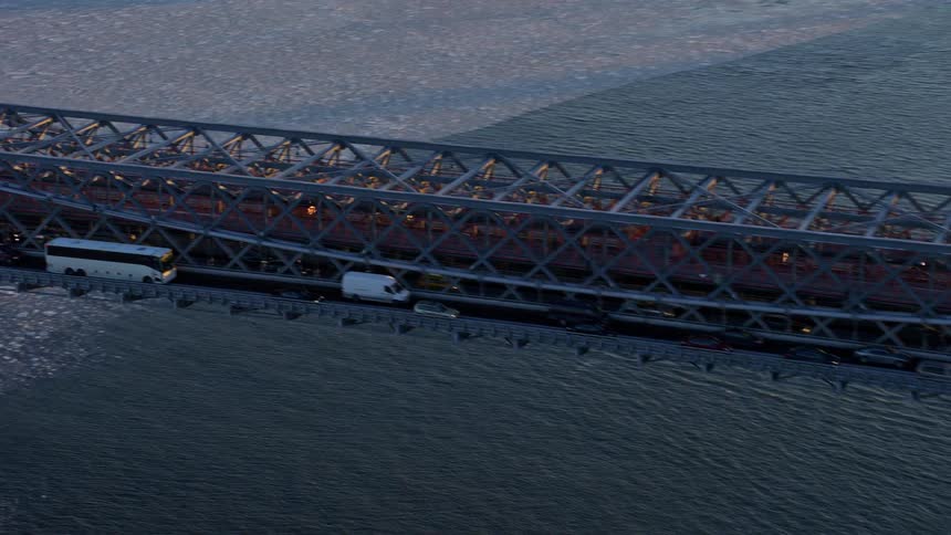 Traffic moving across a bridge over a large body of water that is near a city skyline