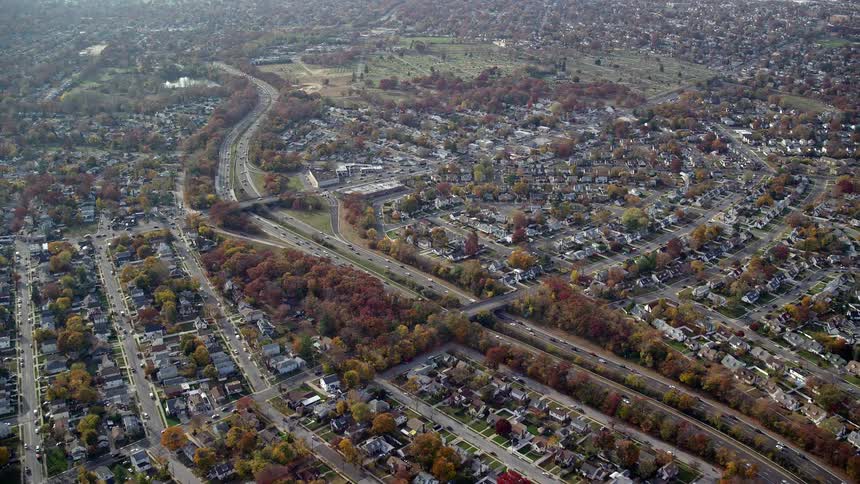 Aerial of a busy separated highway through the middle of a large suburban area