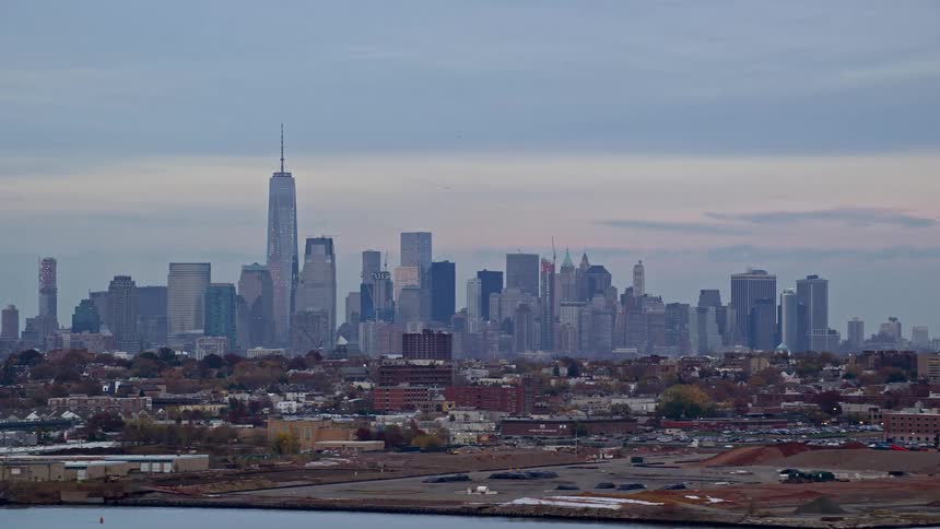 View of an urban city by the seaside with skyscrapers on the horizon and the morning sky