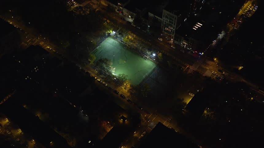 A city with low buildings and a small field is shown at night