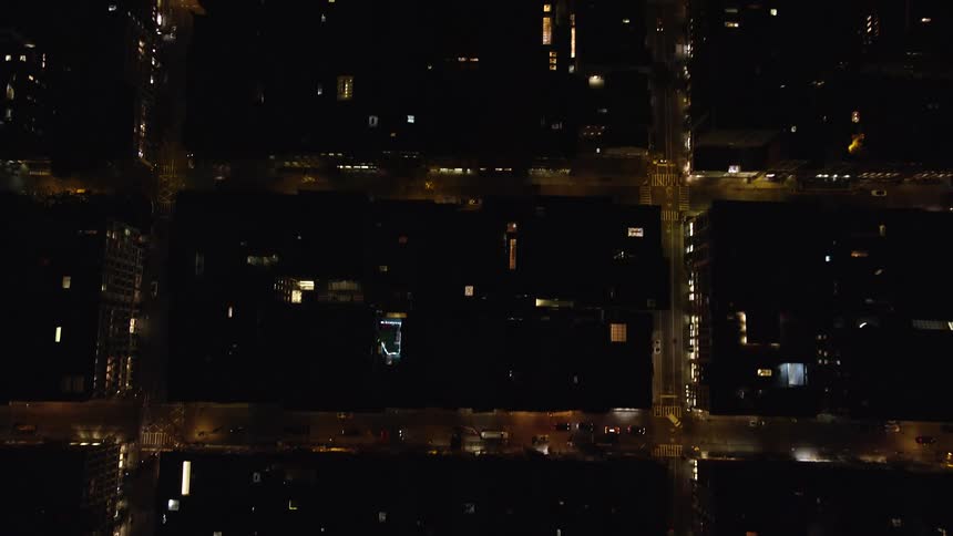 An aerial view of a city at night and the streets are lit up with streetlights
