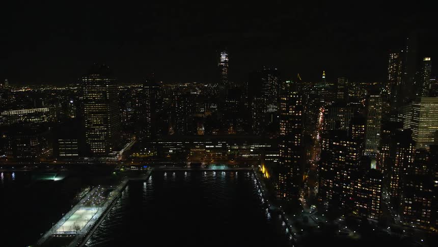 Aerial view of a nighttime metropolis by the seaside with illuminated buildings