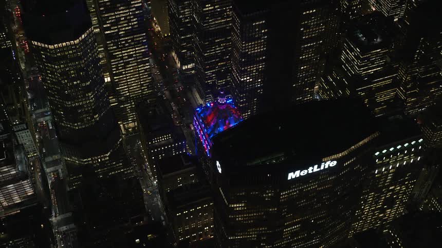 Several buildings in a metropolitan city and the roof of one of them has blue and red lights