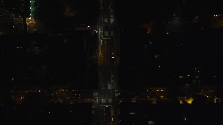 An aerial view of a night city streets with some cars passing by