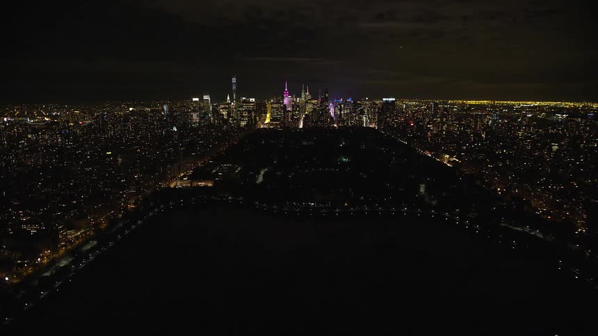 Lights form patterns on water bordering downtown skyscrapers at night
