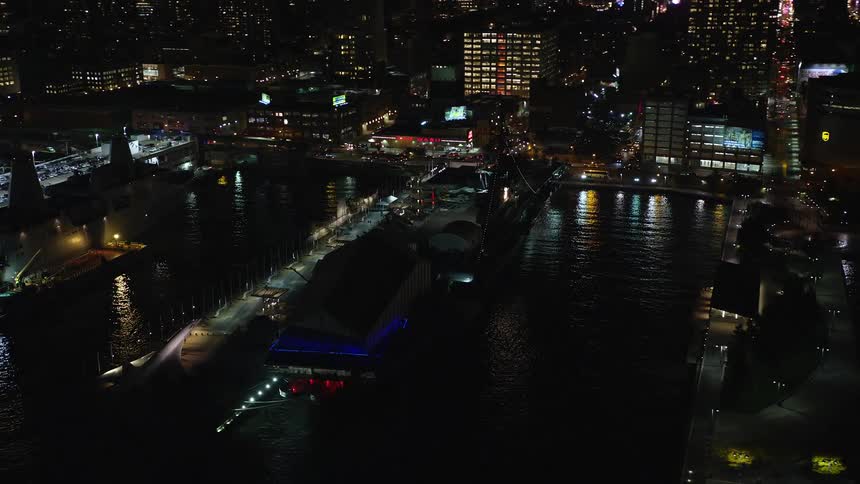 View of boats docked at the port by the edge of a metropolitan city at night
