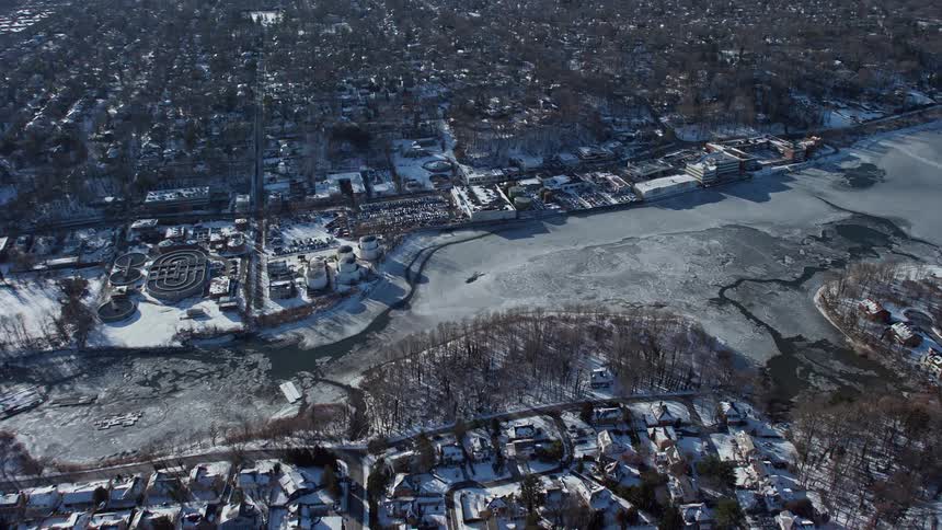 A city with residential buildings mostly covered in snow with icy river due to the weather