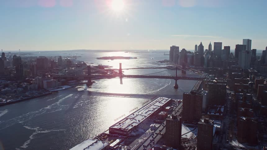 During sunrise in a city with lots of high rise building there is a bridge linking two city