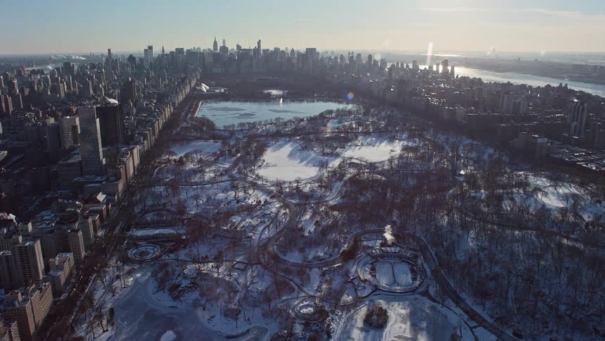Aerial view of a metropolitan city with a central park a serene lake and the morning sun in the background