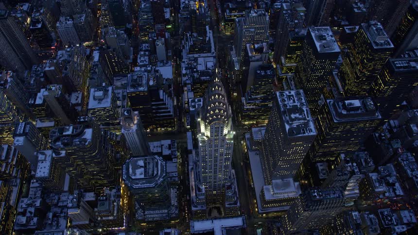 A metropolitan city with huge buildings with the lights on and behind there is a river